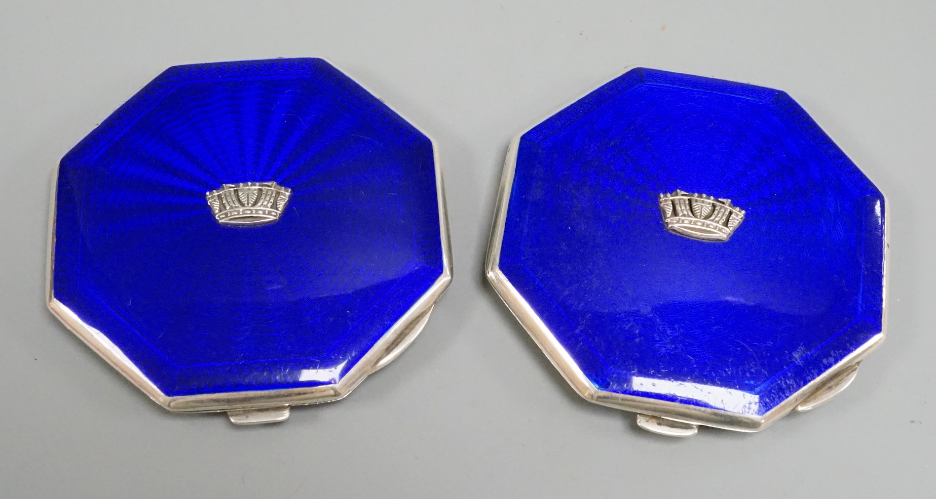 A pair of George VI part engine turned silver and enamel octagonal compacts, with coronet appliqués, John William Barrett, Birmingham, 1941, 77mm.
